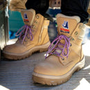 Beige work boots with purple laces on a vehicle floor.