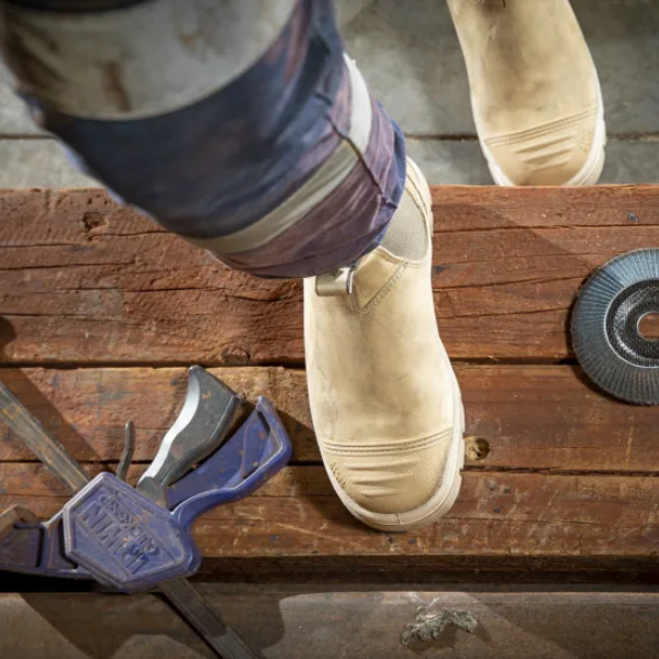 Worker wearing Steel Blue Hobart safety boots on timber planks in a rugged site environment – Kustom Workwear.