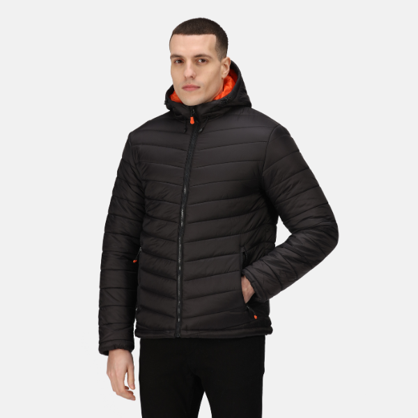 Man wearing a black puffer jacket with orange accents on a white background. Side profile of the Regatta TRA527 Heated Jacket in black with hands in pockets and zipped front – Kustom Workwear branded image.