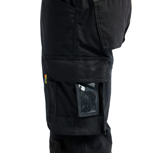 Close up view of D pocket on left leg of black work pants against a white background.