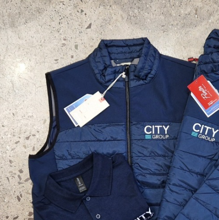 Navy bodywarmer, padded jacket and polo shirt with embroidered company logo showing a coordinated branded workwear uniform set.