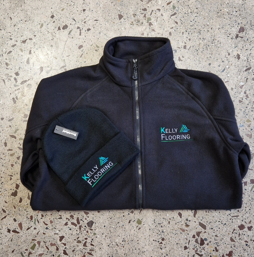 Navy fleece jacket and matching beanie hat with embroidered company logo showing professional branded workwear and headwear set.