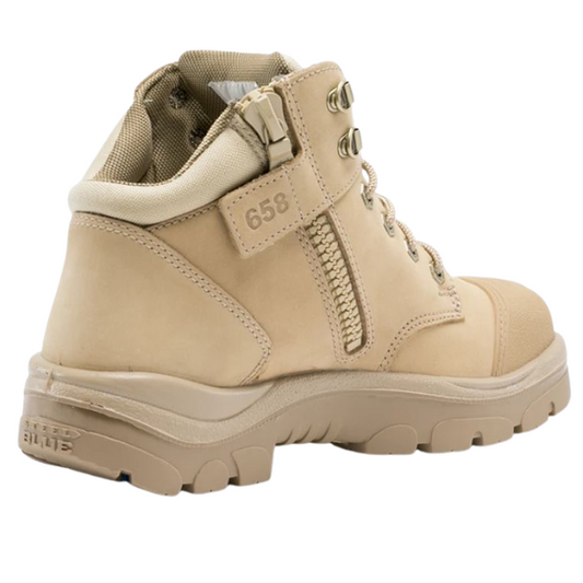 Angled shot of tan safety footwear with ankle support and rugged tread sole.